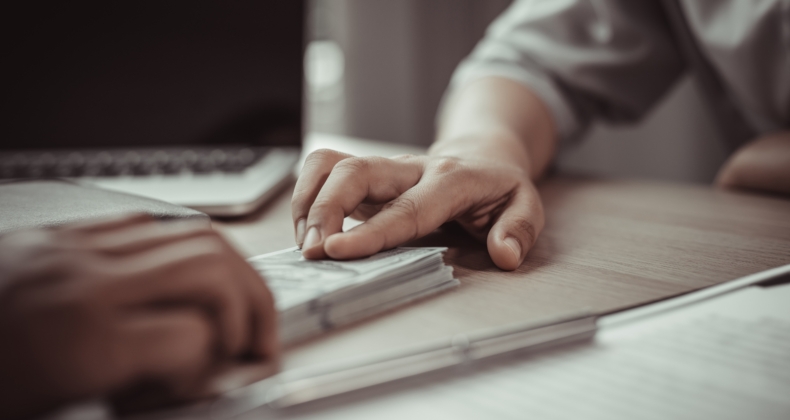 ruka zadržuje peníze na stole